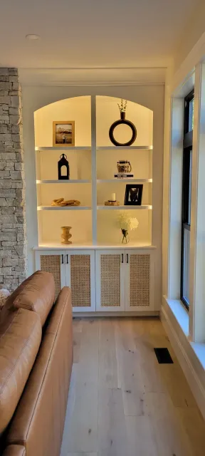 Built-in white shelves with decor in a bright hallway beside a tan sofa and window