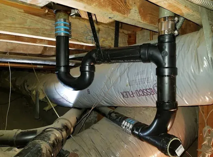 New PVC drain, waste and vent piping installed under a floor joist bay