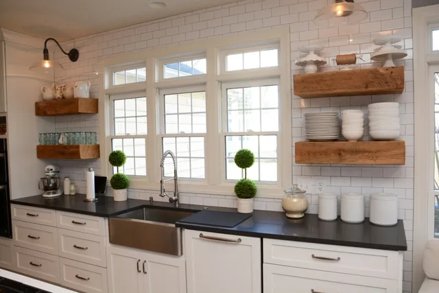 White shaker kitchen with subway tile, reclaimed wood shelving and farmhouse sink