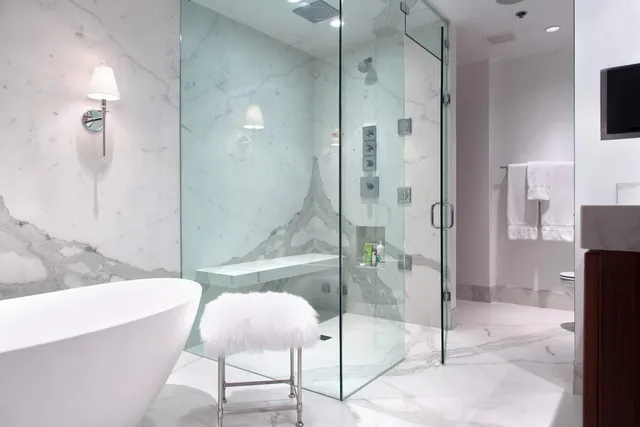 Porcelain Slabs — master bathroom with freestanding tub, marble walls, and glass shower enclosure. Boston area.