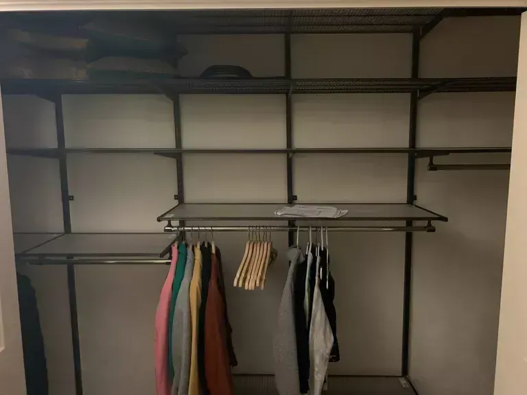 Empty walk-in closet with hanging rods, shelves, and a few clothes on hangers