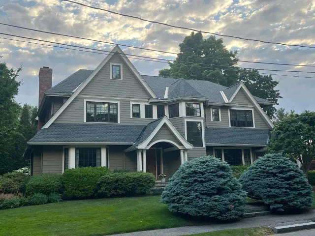 Large gray home exterior with new roof, white trim, and landscaped front yard