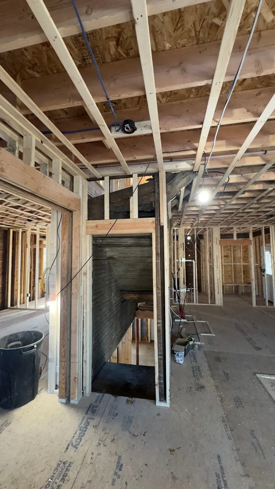 Interior view of a building under construction, showing wooden framing and stairwell.