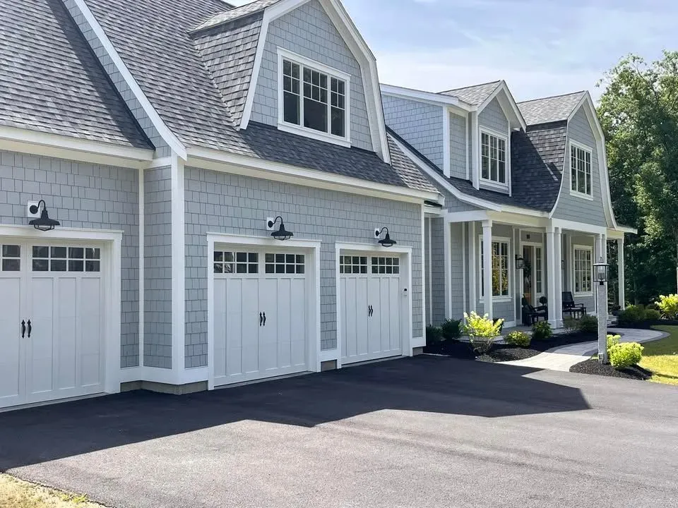 A house with three garage doors and a driveway in front of it