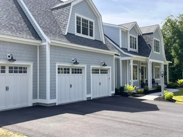 A house with three garage doors and a driveway in front of it