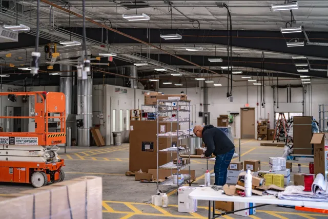 Interior of commercial warehouse under construction with conduit, lighting, and workstations