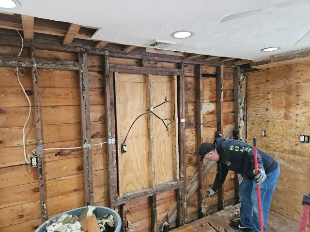 A man is working on a wooden wall in a room.