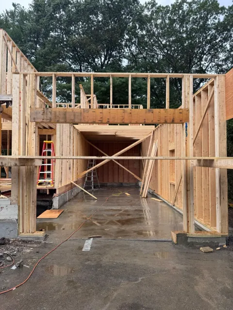 Wooden framing of a residential garage construction site featuring an open doorway and exposed wall studs.