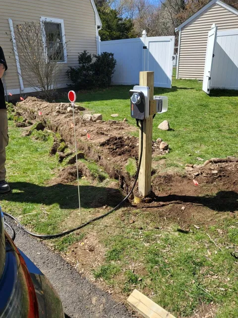 Installation of an electric vehicle charging station in a residential yard.