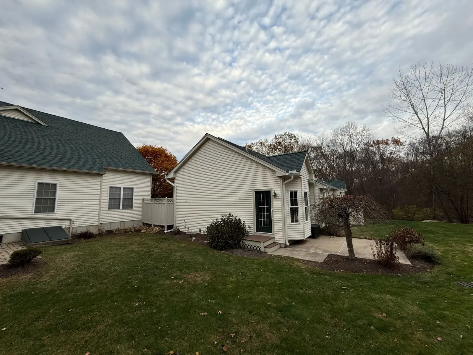 Small white house with green roof and attached garage on a cloudy day