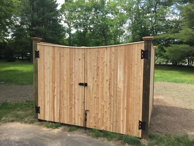 A wooden gate is sitting in the middle of a grassy field.