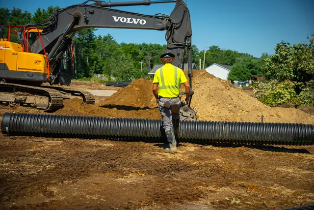 A Woods crew member working the culvert pipe run ahead of the excavator