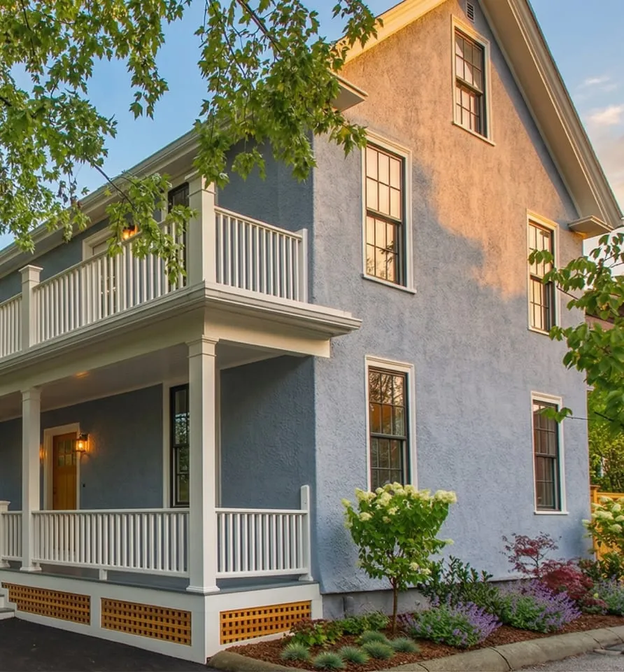 A two-story blue house with white trim at 17 Smith Place features a covered front porch, surrounded by landscaped plants and trees.