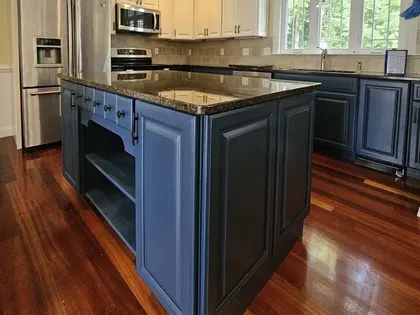Modern kitchen with blue island, granite countertop, stainless appliances, and hardwood floors