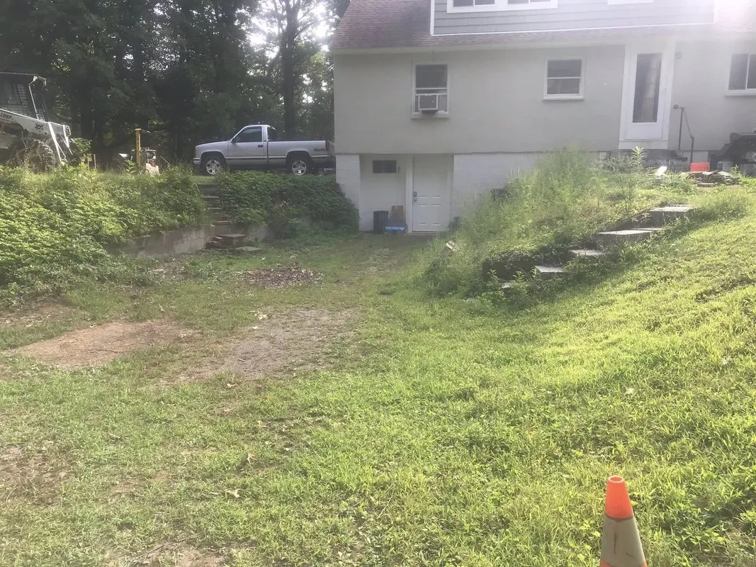 Overgrown hillside before retaining wall installation - Before