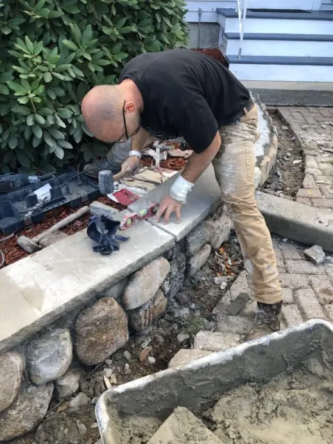 Man working on stone wall with tools and cement mix