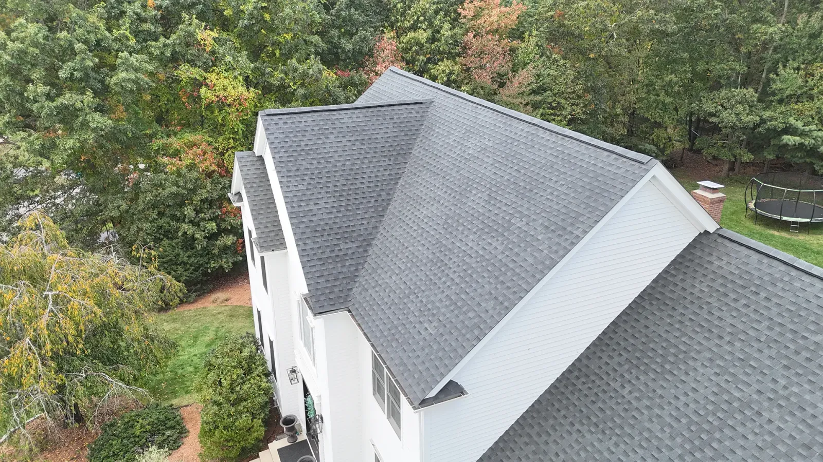 Aerial view of a white home with a newly installed gray shingle roof