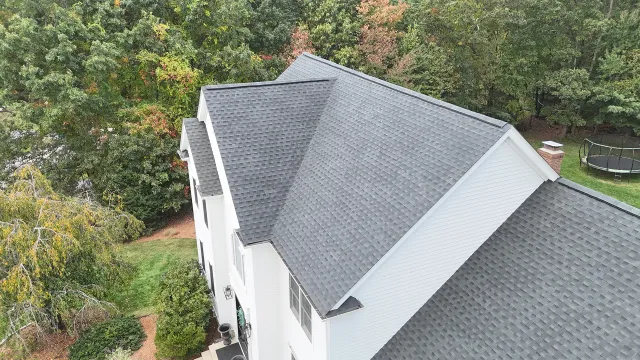 Aerial view of a white home with a newly installed gray shingle roof