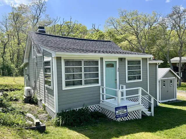 Gray single-story cottage in Plymouth, MA with a new CertainTeed Landmark Pro Moire Black asphalt roof, teal front door, and a covered front entry with white railing