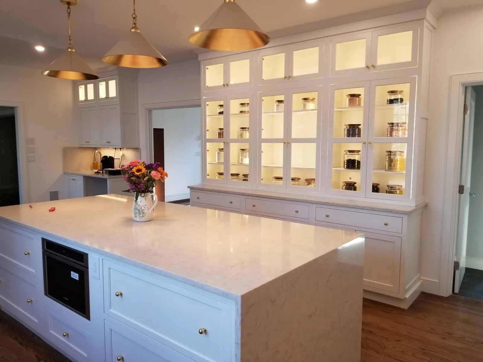 Kitchen with lit glass display cabinets and quartz island