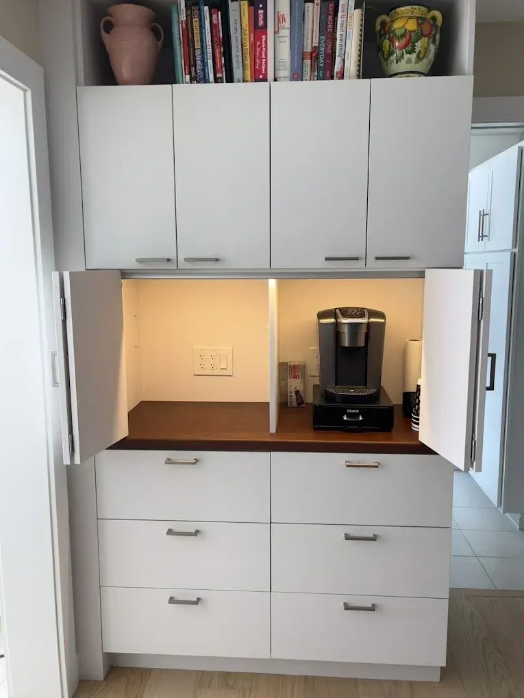 Under cabinet lights installed in a white kitchen illuminating the counter top and kitchen appliances
