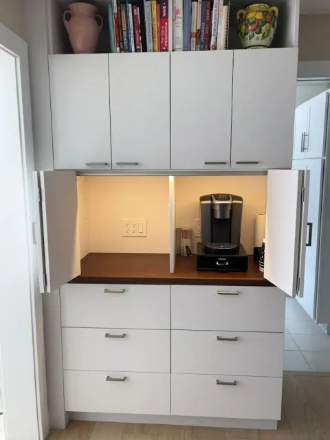 Under cabinet lights installed in a white kitchen illuminating the counter top and kitchen appliances