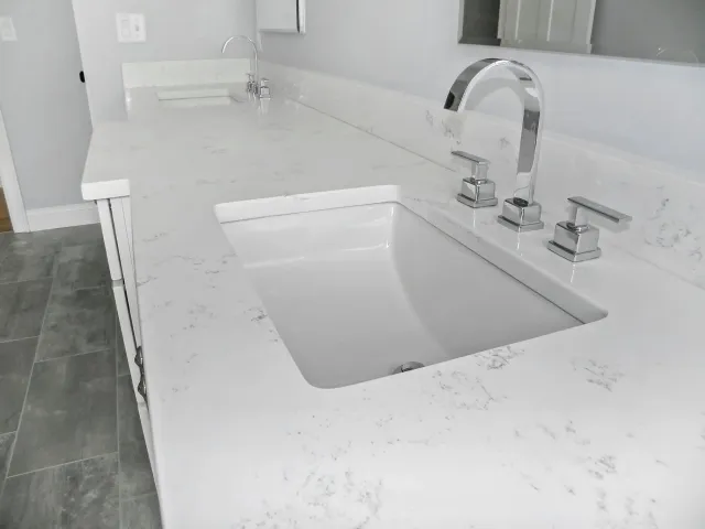 White quartz countertop with rectangular sink and chrome faucet.