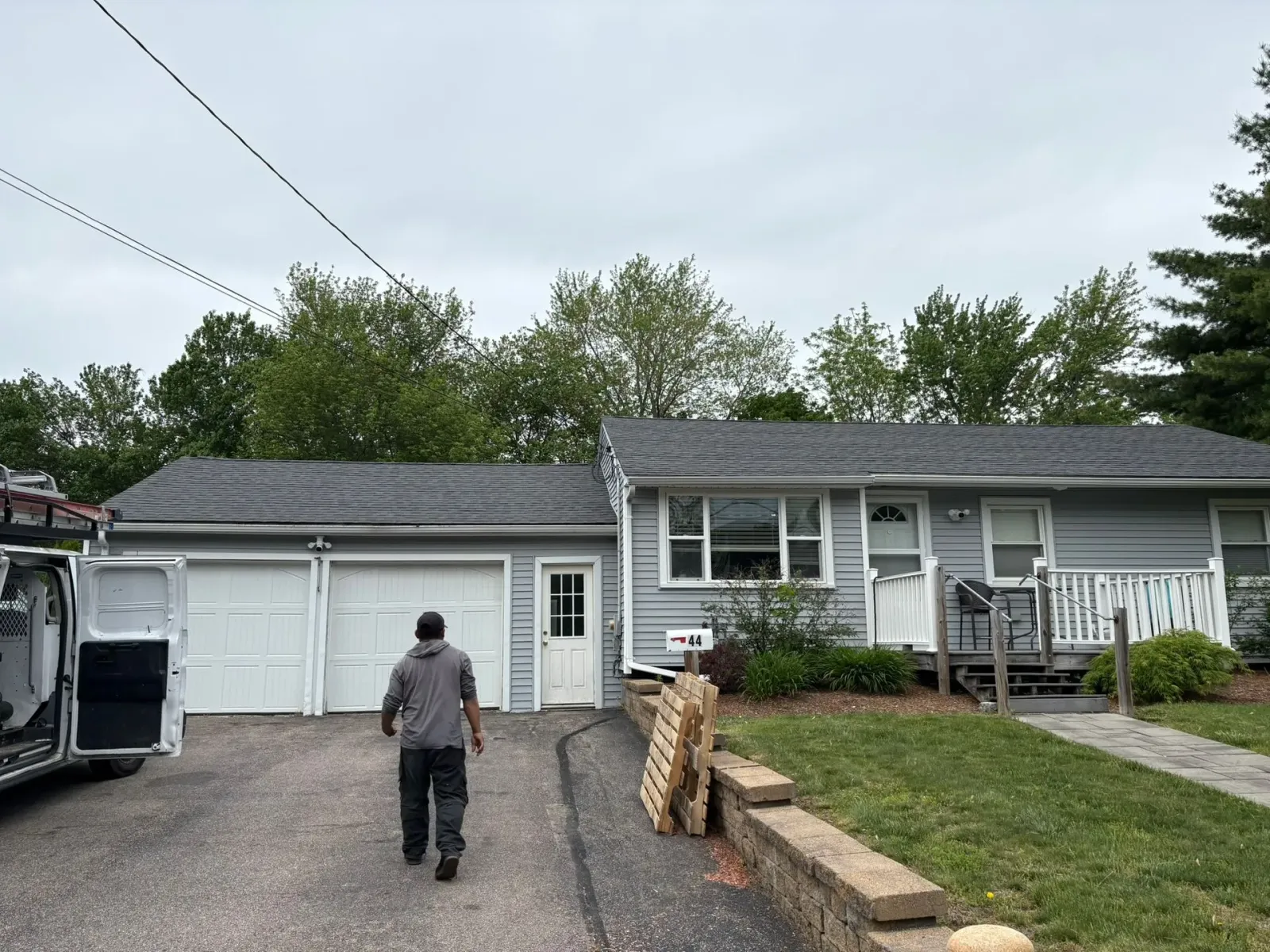 Person walking toward a white garage with a truck parked at the left side of a suburban house.