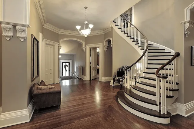 Elegant foyer with curved staircase, hardwood floors, chandelier, and decorative moldings.