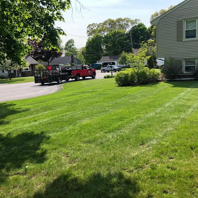 Striped-mown front lawn with the company truck at the curb