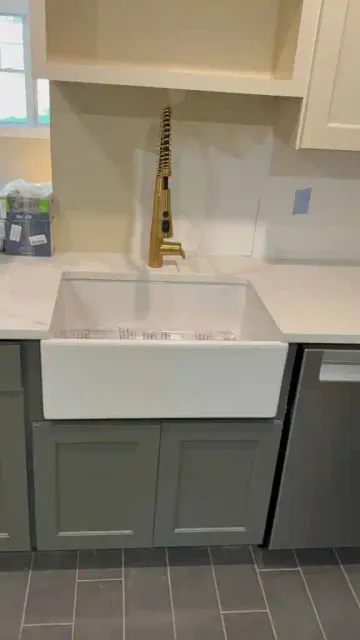 New farmhouse sink with gold faucet in a contemporary kitchen.