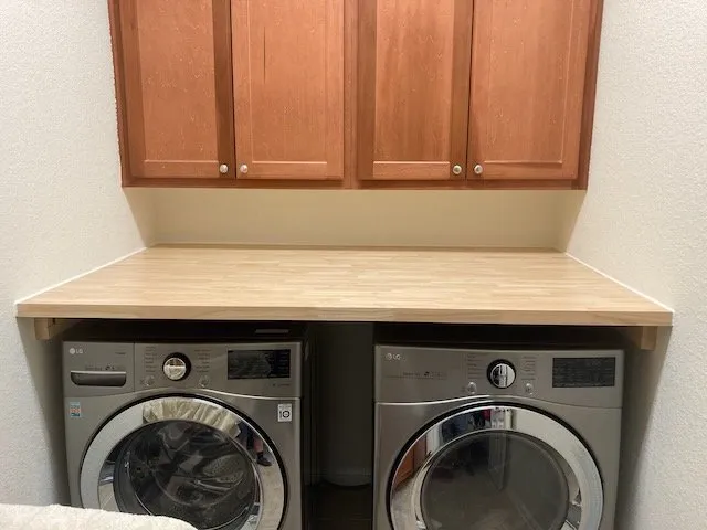 butcherblock laundry folding shelf installed above washer and dryer, including cutouts for hoses and cords