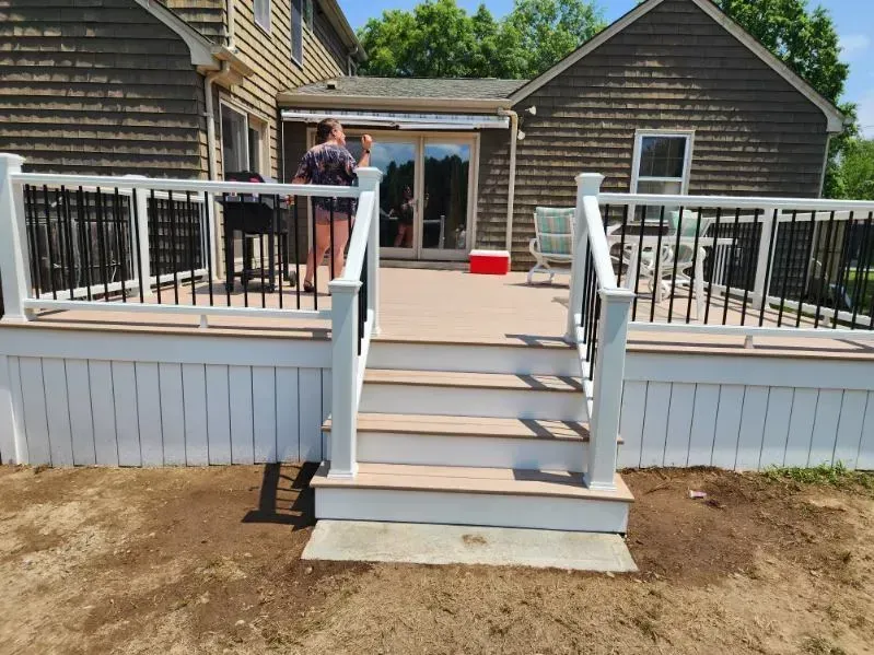 White deck stairs leading to a house patio, with two people standing near the entrance.