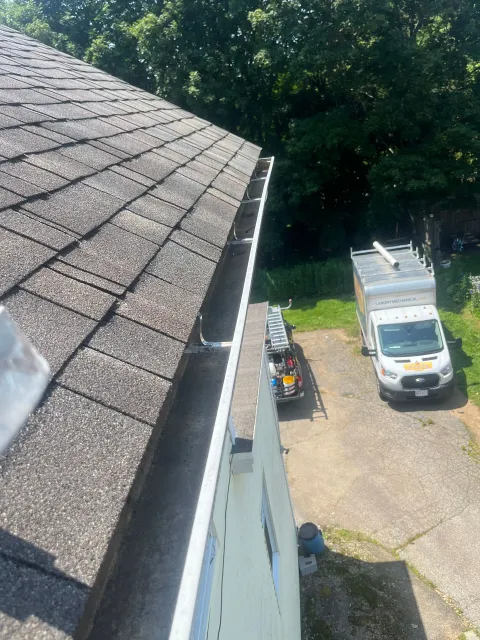 View from a roof edge onto a driveway with a white utility truck and landscaping equipment below