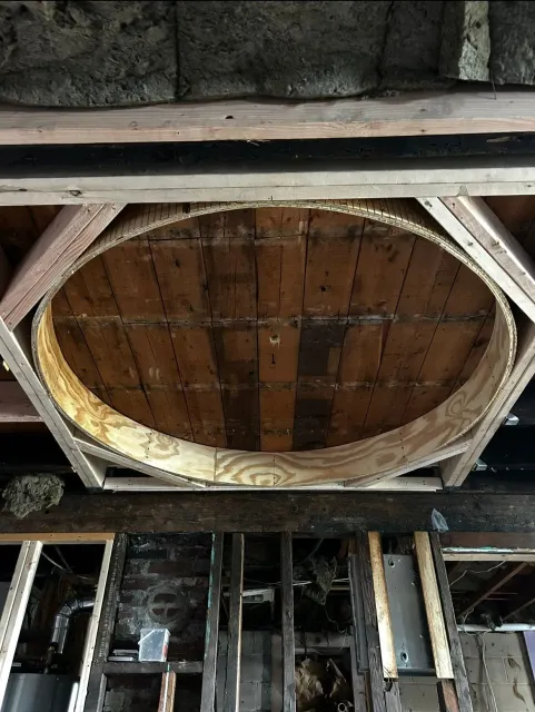 A wooden circle is being built into the ceiling of a building.