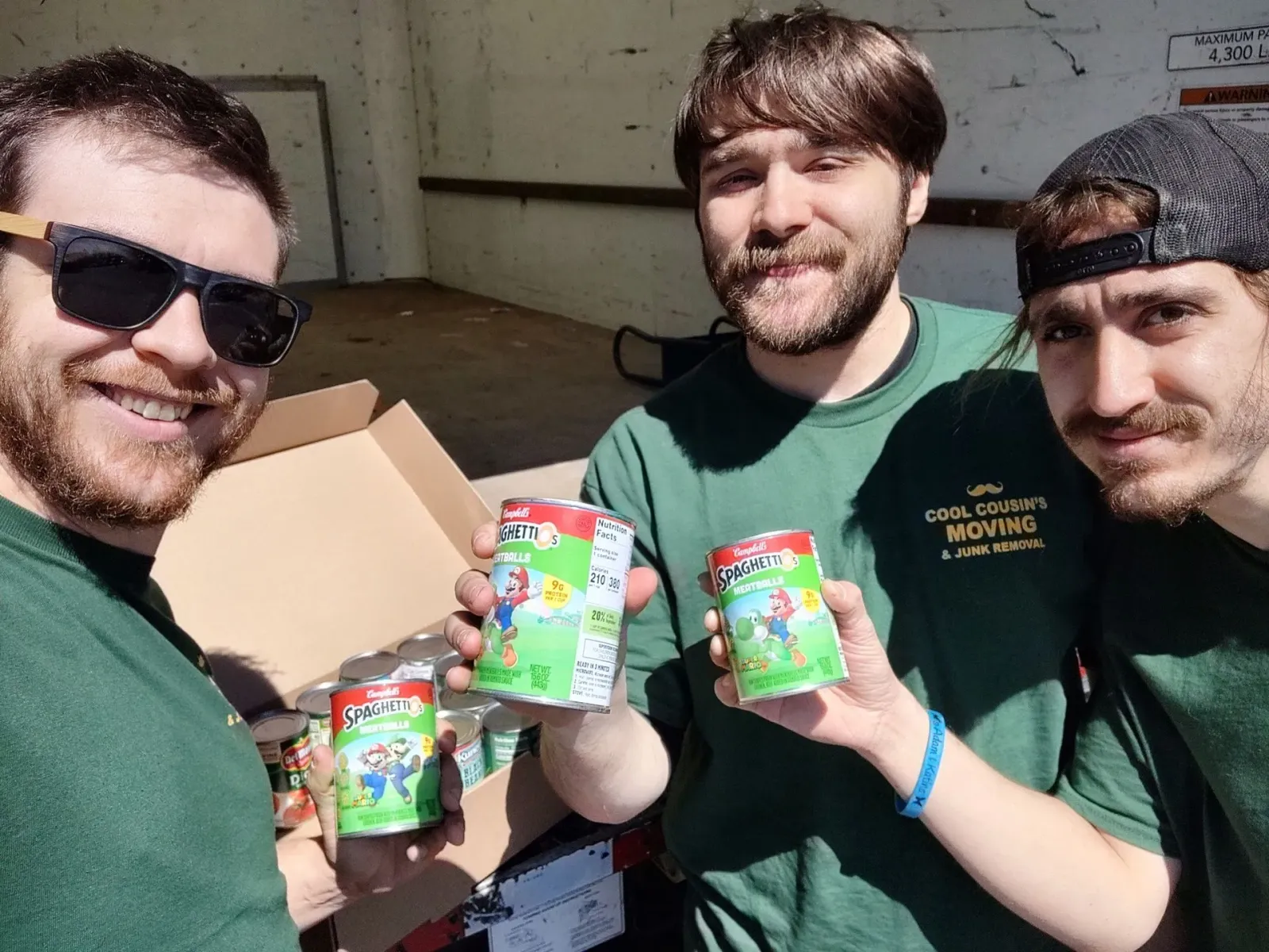 Three friends outdoors holding cans and smiling at the camera