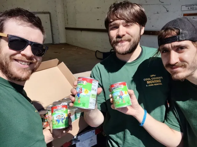 Three friends outdoors holding cans and smiling at the camera