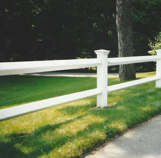 A white fence surrounds a lush green field