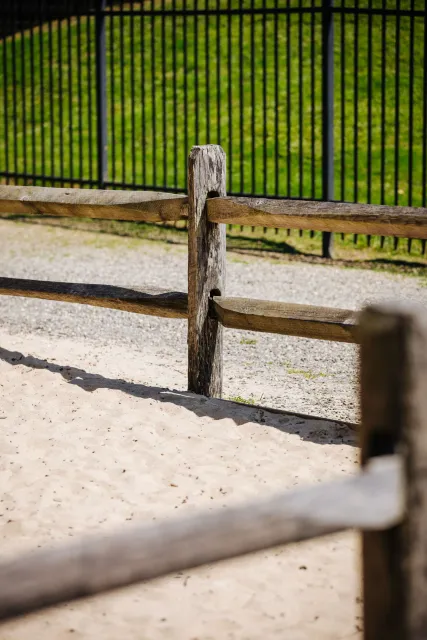 A wooden fence with a metal fence in the background.