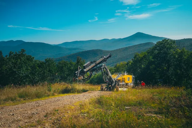Drill rig and crew working on a rocky mountain slope
