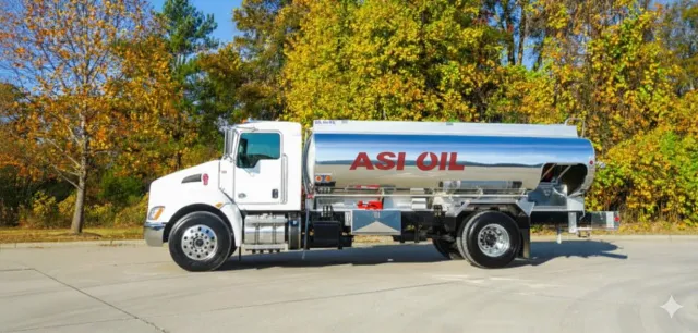 White tanker truck parked near a building with multiple windows.