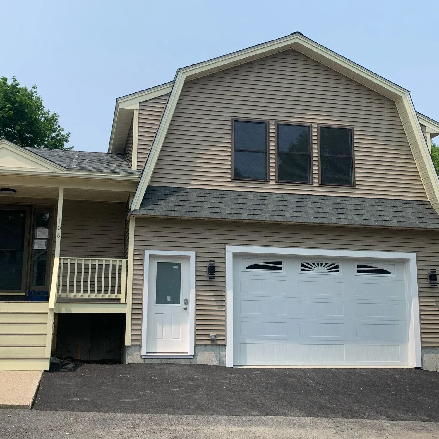 Exterior of a house with beige siding, a white garage door, a white front door, and three windows on the upper floor