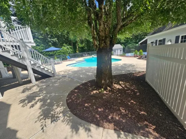 Fresh dark mulch around a tree beside a backyard pool in Hudson, NH