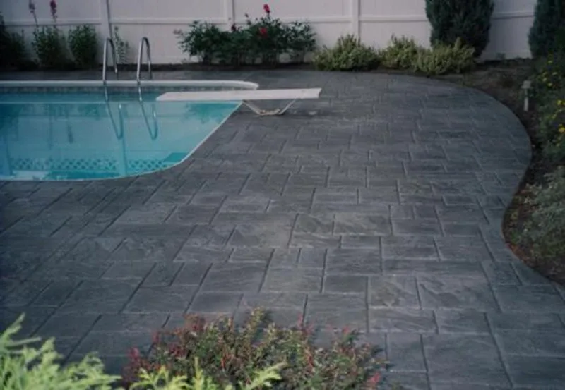 Dark stamped concrete pool deck with diving board