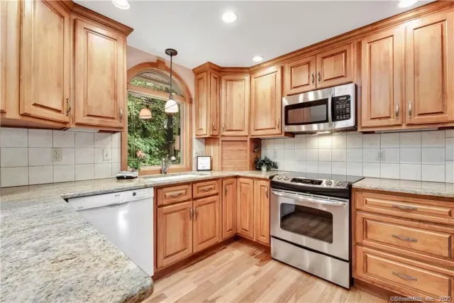 Kitchen with wooden cabinets, stainless steel appliances, and granite countertops.