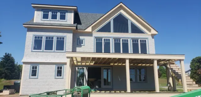 A large white house with a large porch is being built.
