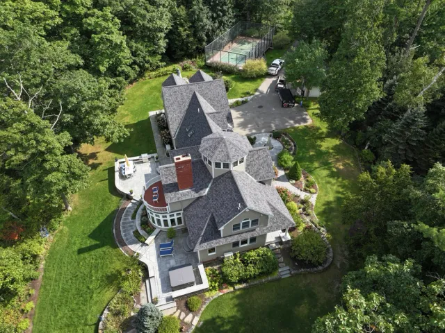 Aerial view of a large house with a pool and tennis court