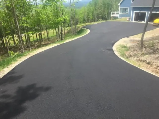 A curvy driveway leading to a house on a hill.