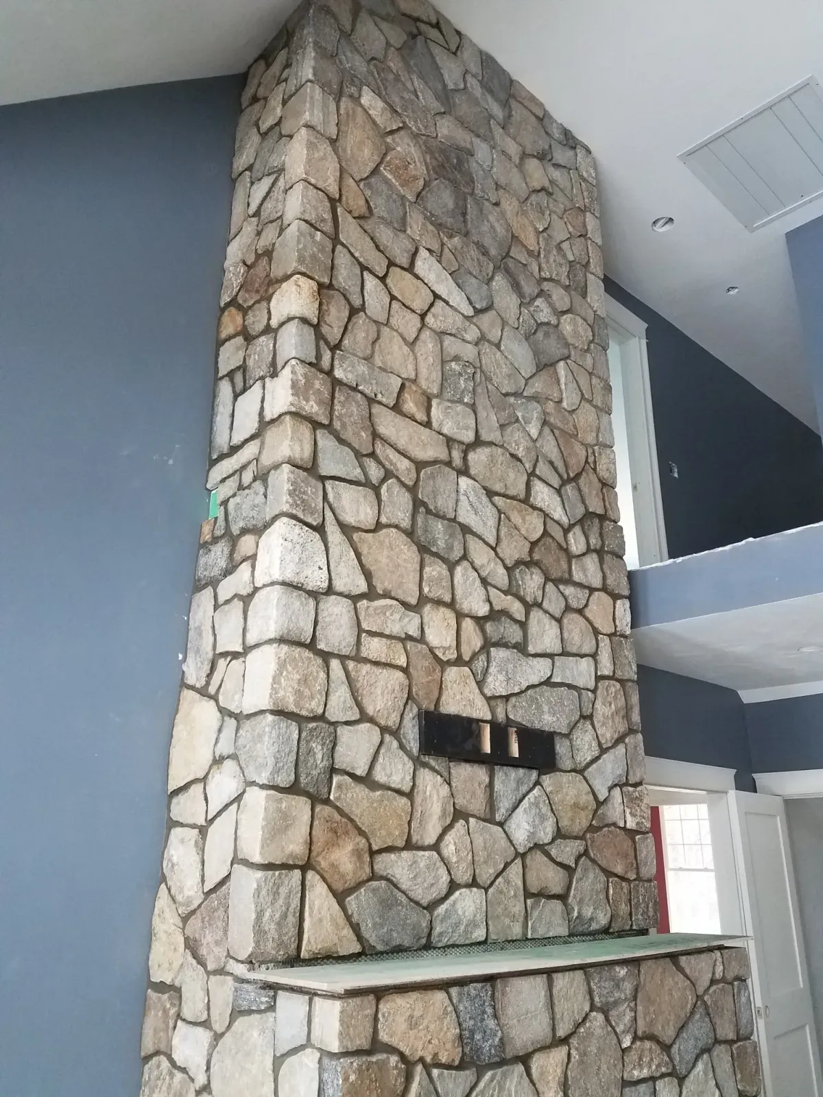 Stone fireplace with a light-colored hearth, in a room with blue and white walls.