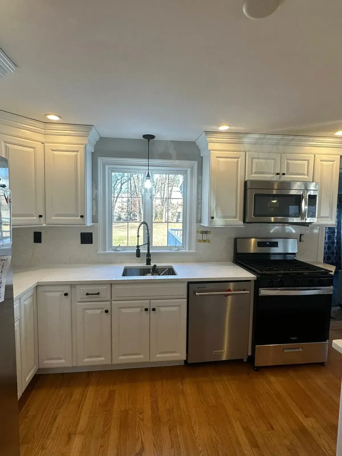 White kitchen cabinets, stainless steel appliances, and a window above the sink.